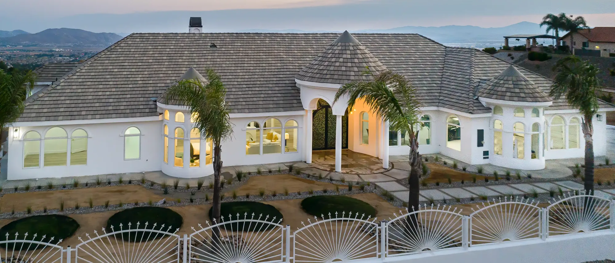Front of a white stucco home with a tile roof at dusk