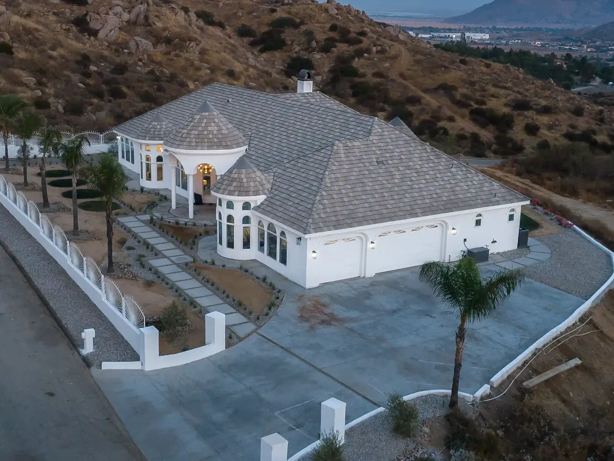 Home with a tile roof and round turrets on a hillside lot